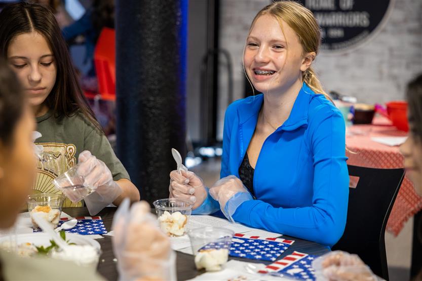 A girl wearing a blue jacket makes a parfait